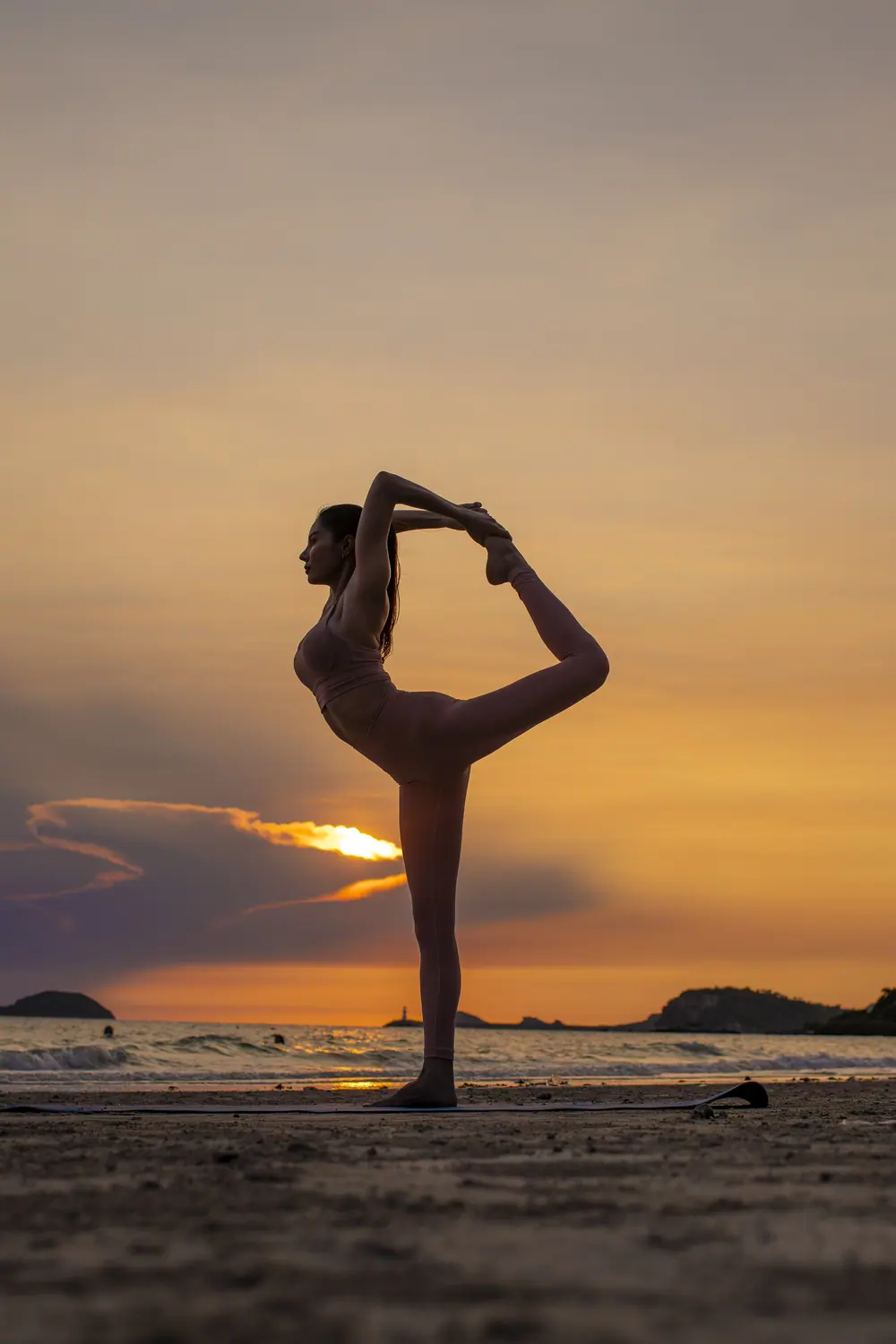 Yoga als Silhouette vor dem Sonnenuntergang am Meer